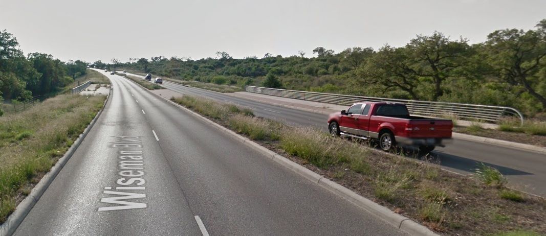 Red pickup on a highway beside a grassy median under a cloudy sky