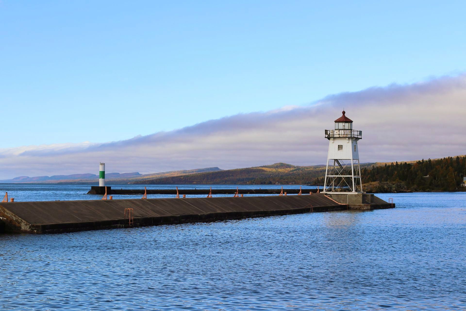A lighthouse is sitting on top of a pier in the middle of a body of water.