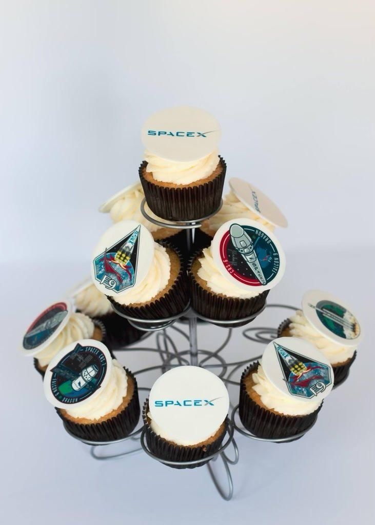 Cupcakes with SpaceX logos and space-themed images displayed on a tiered stand.