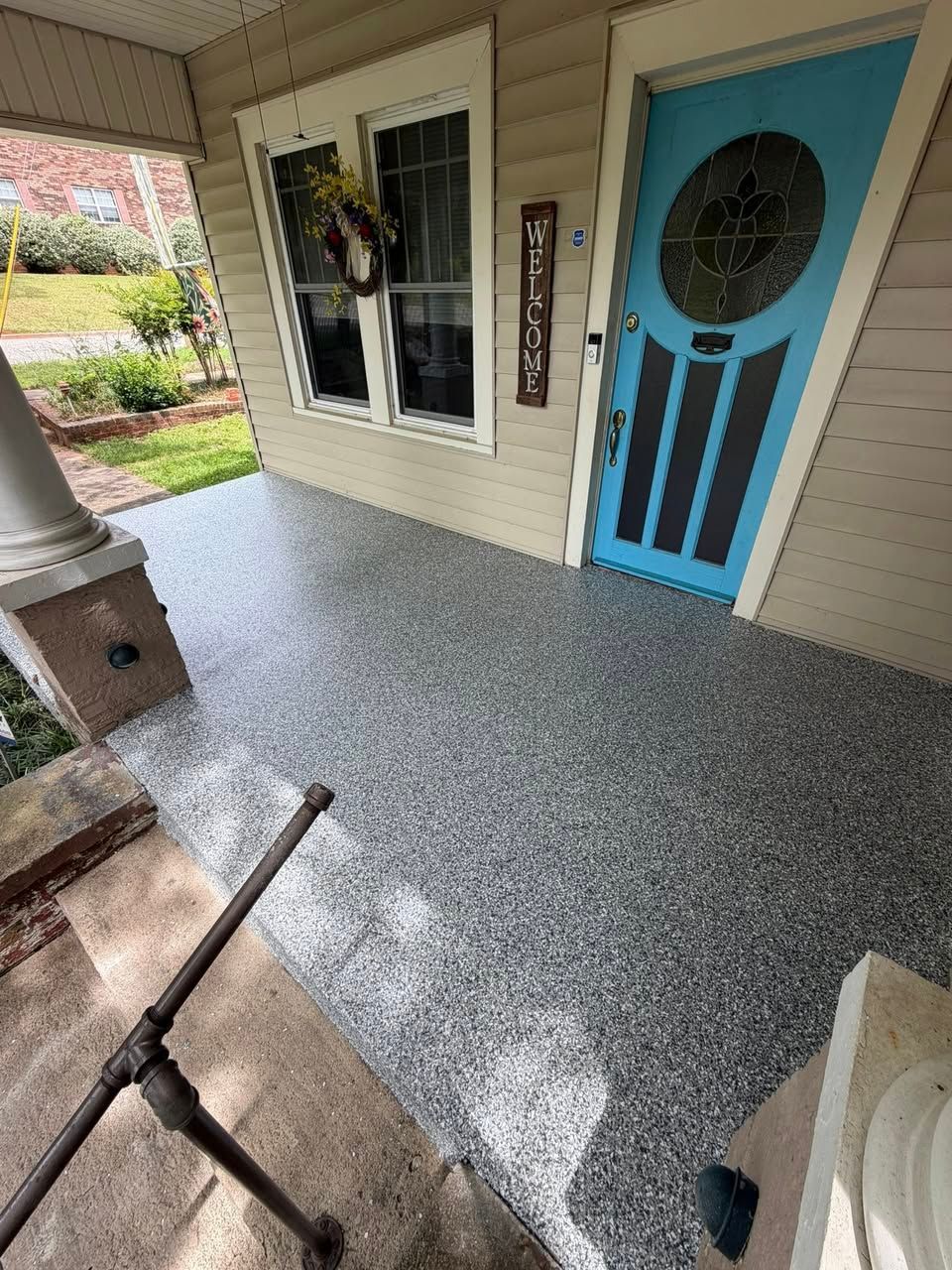 Front porch with gray speckled floor, blue door, window, and chair railings.