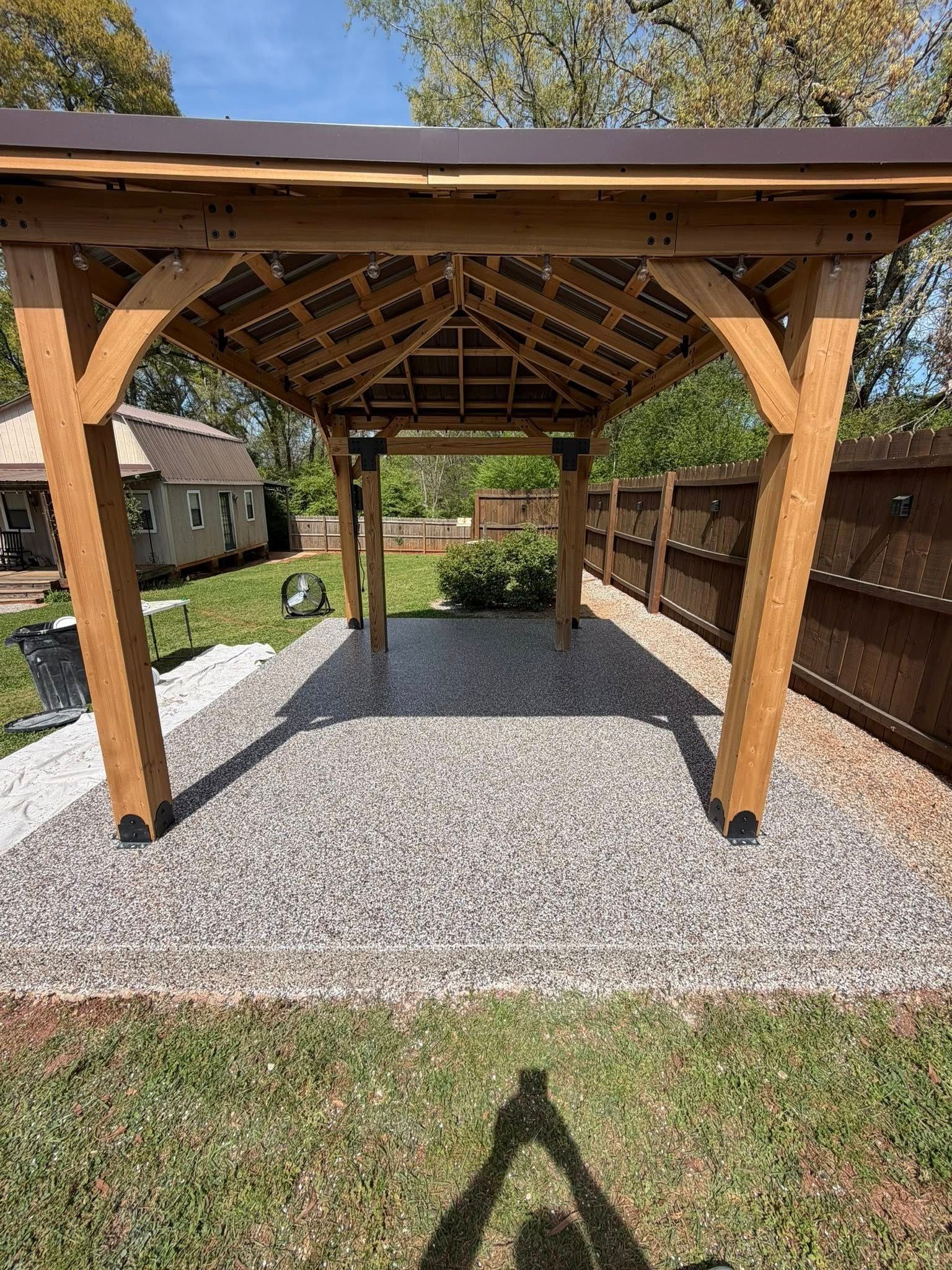 Wooden pergola over a gravel patio and grass lawn in a backyard garden