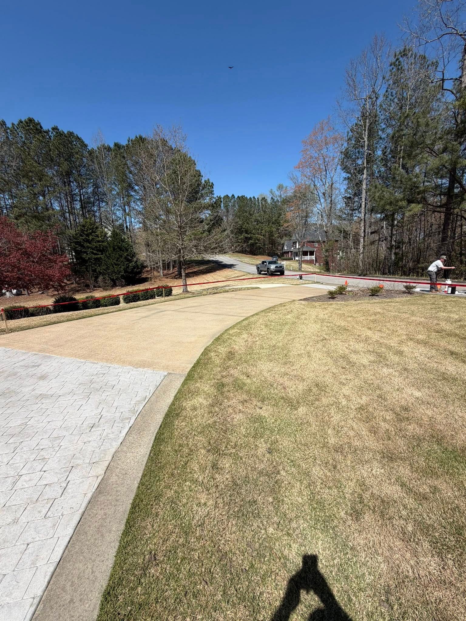 Curved gravel path beside grassy hill and trees under a clear blue sky