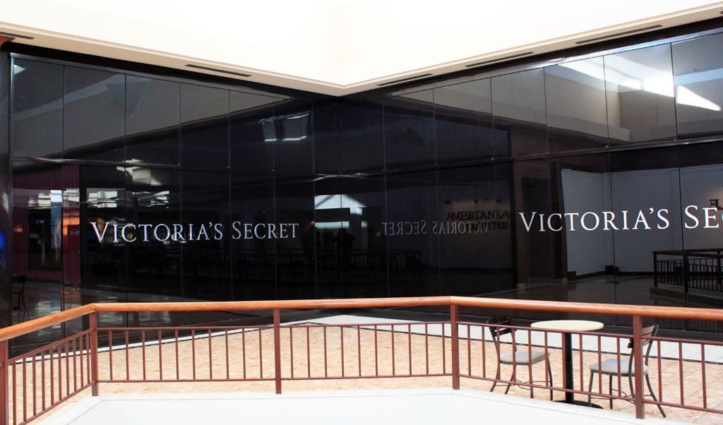 Victoria’s Secret storefront with dark reflective windows and a low orange railing in front