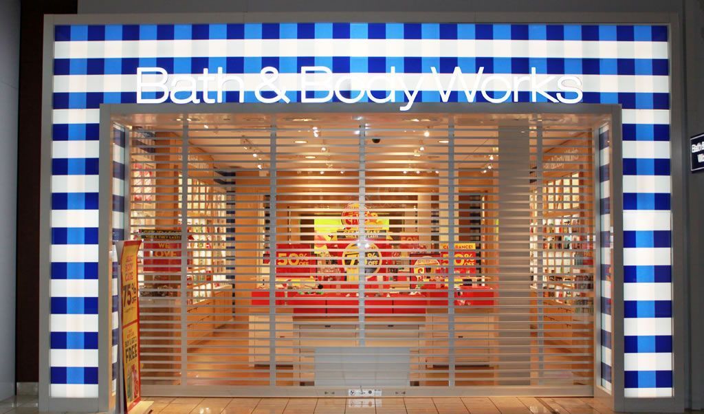 Closed storefront with blue-and-white striped facade and “Bath & Body Works” sign behind a metal gate