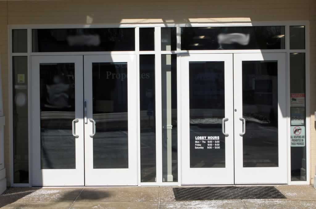 Glass storefront entrance with white double doors and dark window panels