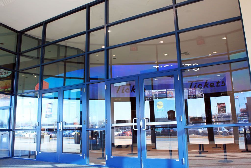 Glass storefront entrance with blue awning and reflections on the doors