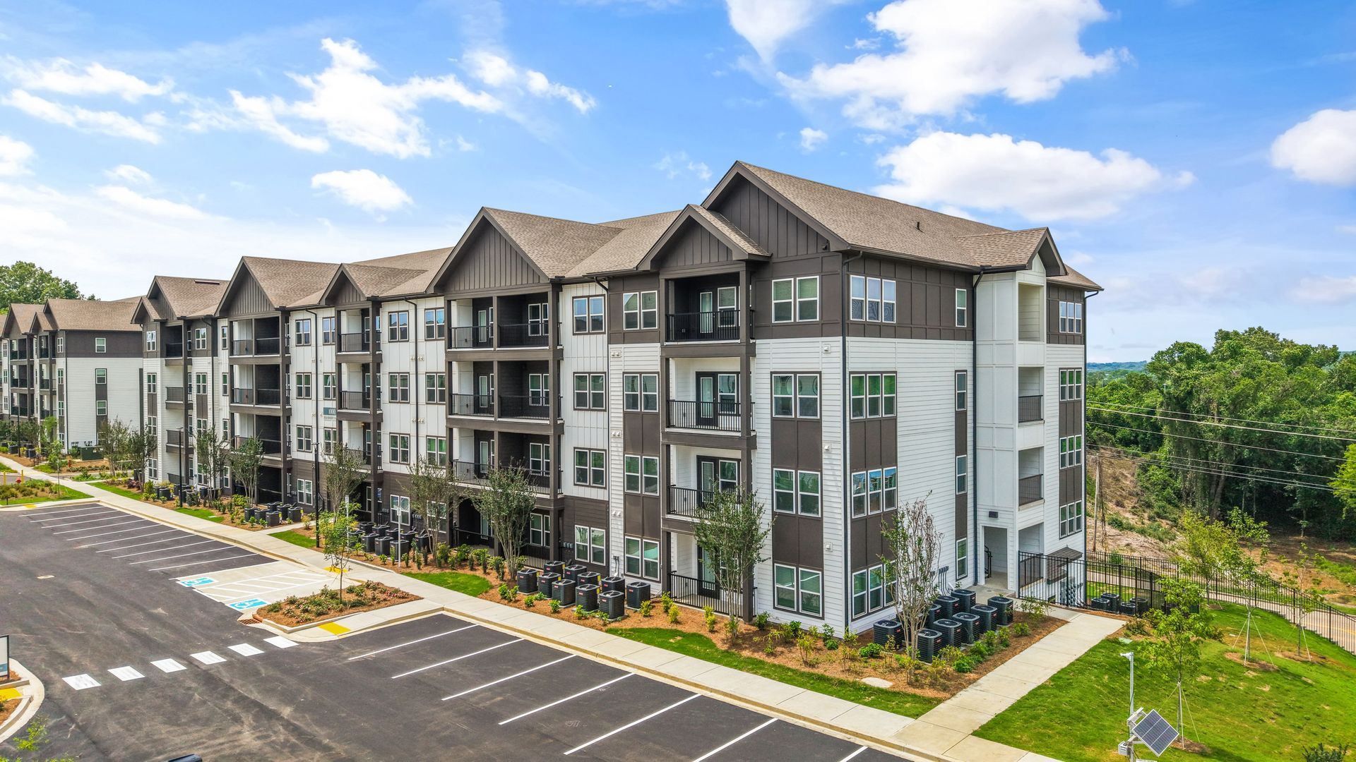 Modern apartment building with white siding, black trim, and gabled roofs under a blue sky.