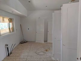 Interior room with white walls, doors, and bare floor under construction.