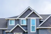 Gray house exterior with multiple roof gables, white trim, and rectangular windows.