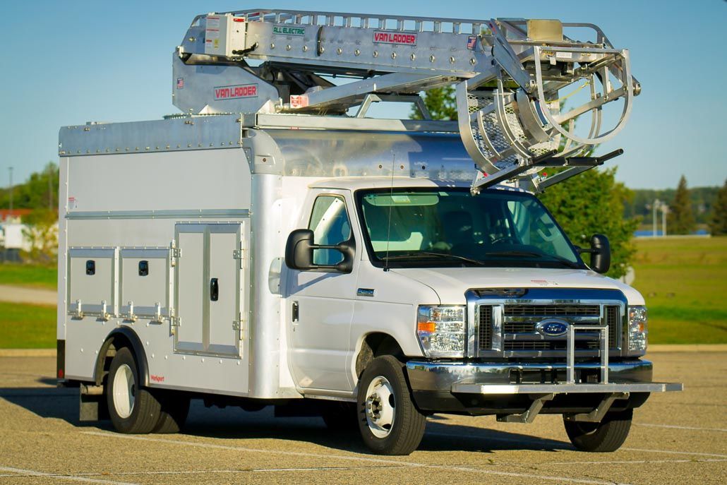 White utility truck with aerial lift on a paved area.