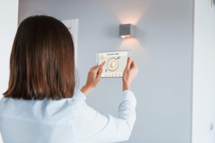 Woman uses a tablet to control a wall light.