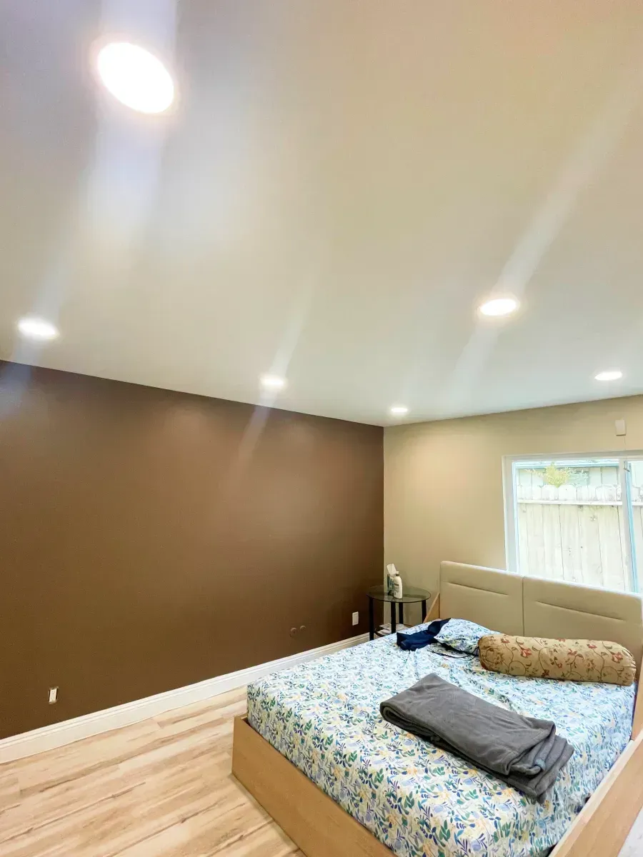 Bedroom with a brown accent wall, beige walls, and a floral patterned bed.