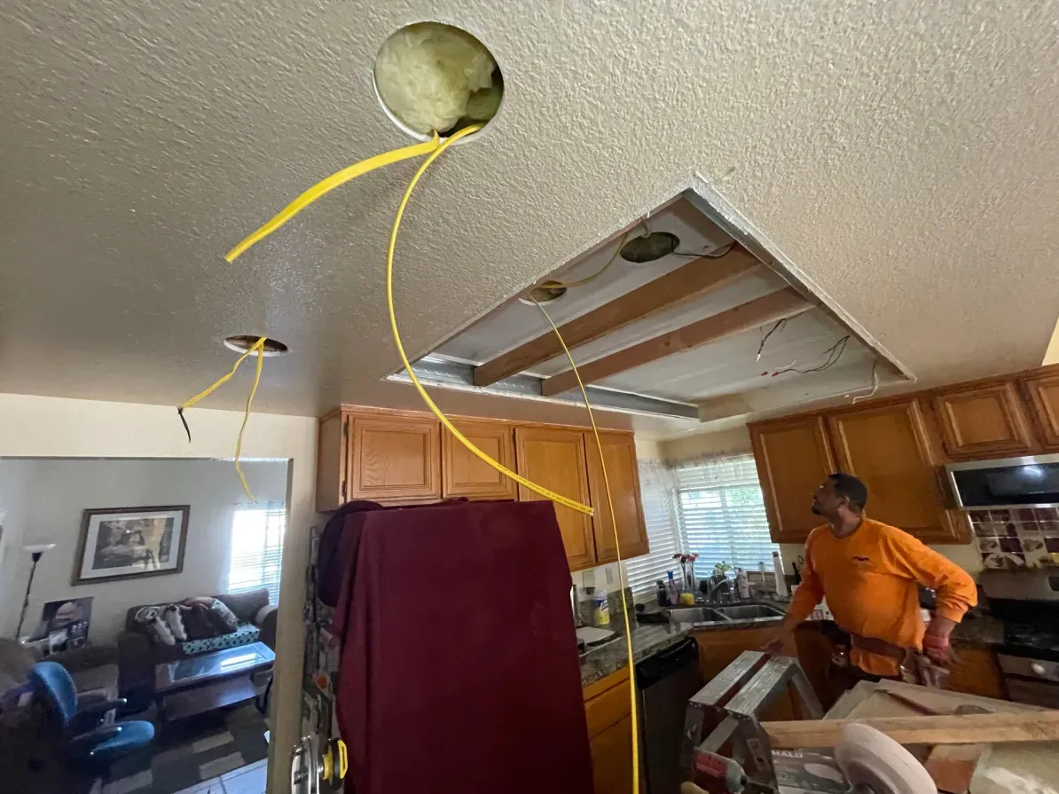 Ceiling with holes; electrician working in kitchen, yellow wiring visible.