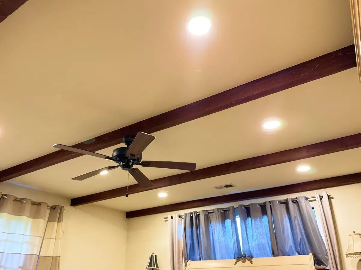 Beige ceiling with dark brown beams, a ceiling fan, and recessed lights.