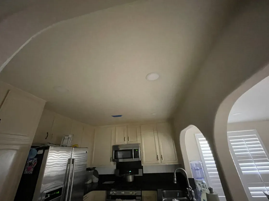 Kitchen interior with arched doorways, cabinets, appliances, and a stainless steel refrigerator.