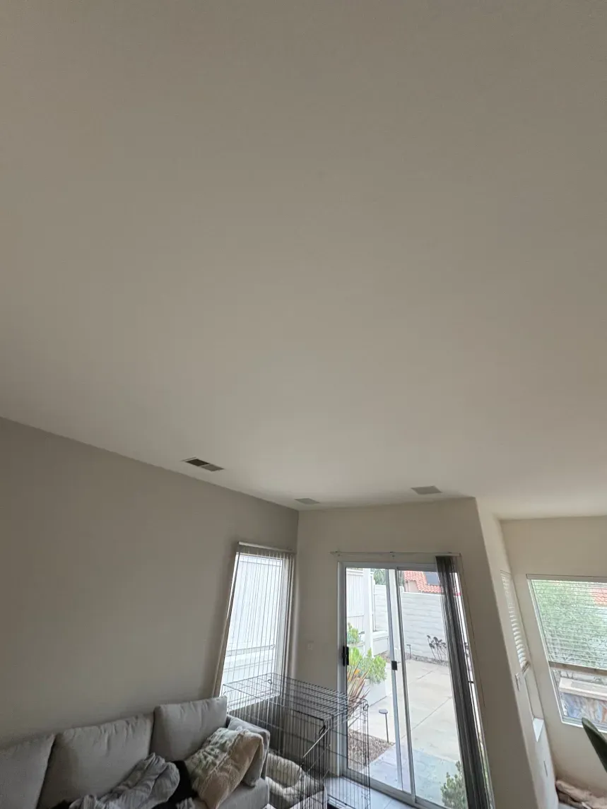 Interior view of a room with a couch, window, and sliding glass door.