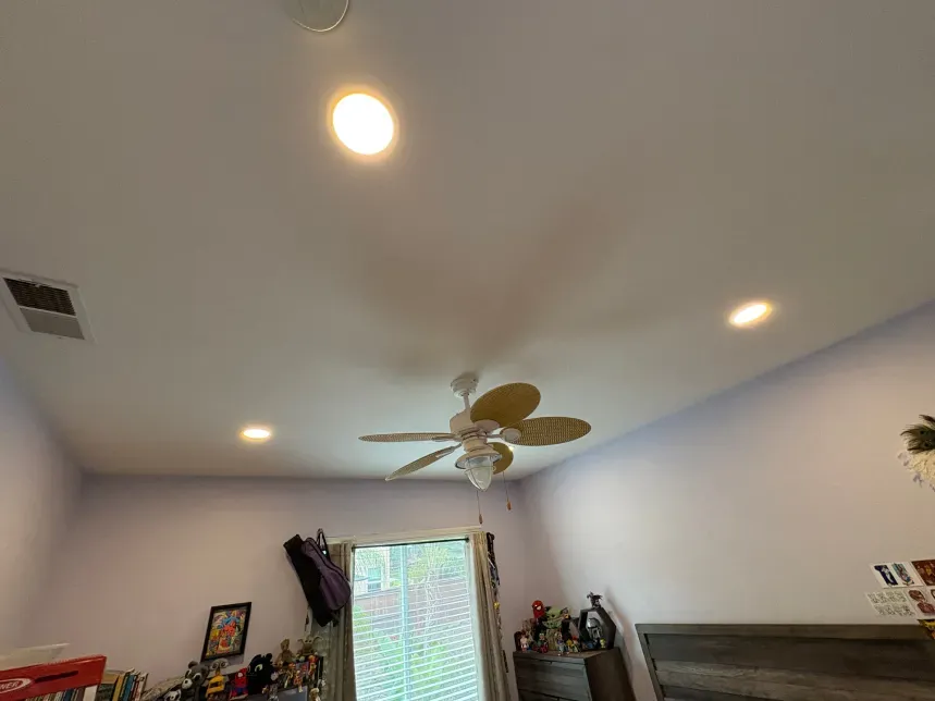 Ceiling with recessed lights, ceiling fan, and window. Pale purple walls.