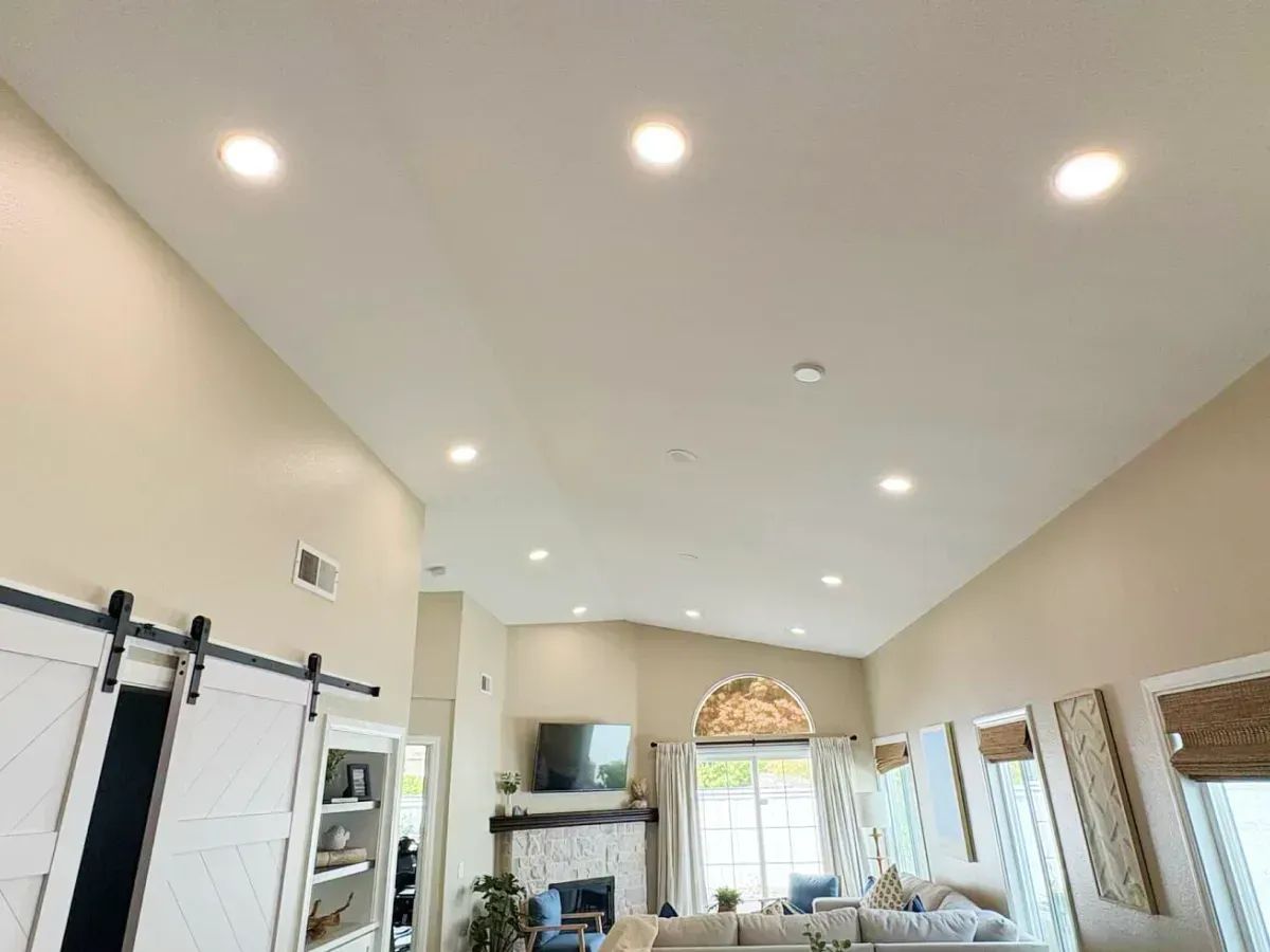 Bright modern kitchen with vaulted ceiling, skylights, white cabinets, and large glass doors leading outside