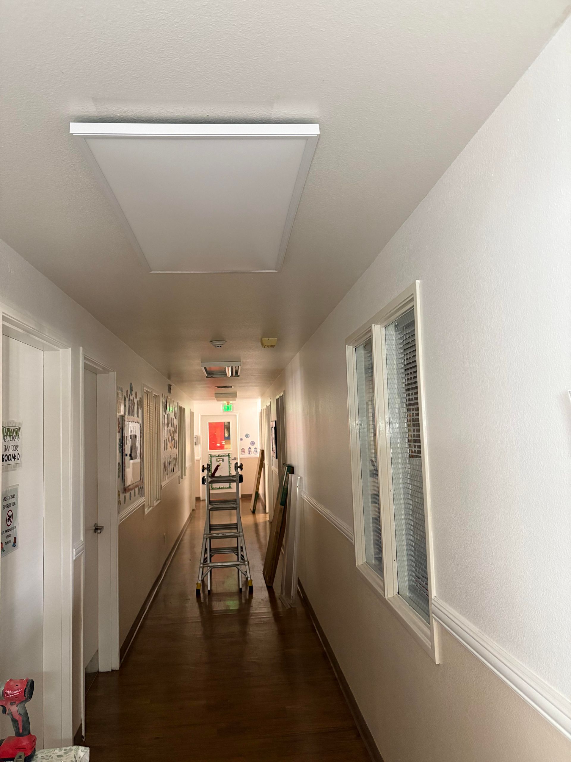 A tall hallway with stairs, ladder, and a light fixture on the ceiling.