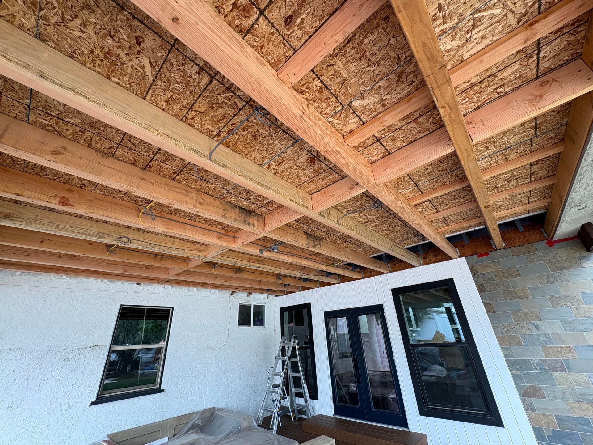 Fireplace under construction, framed with wood studs. Concrete hearth and sheetrock visible.