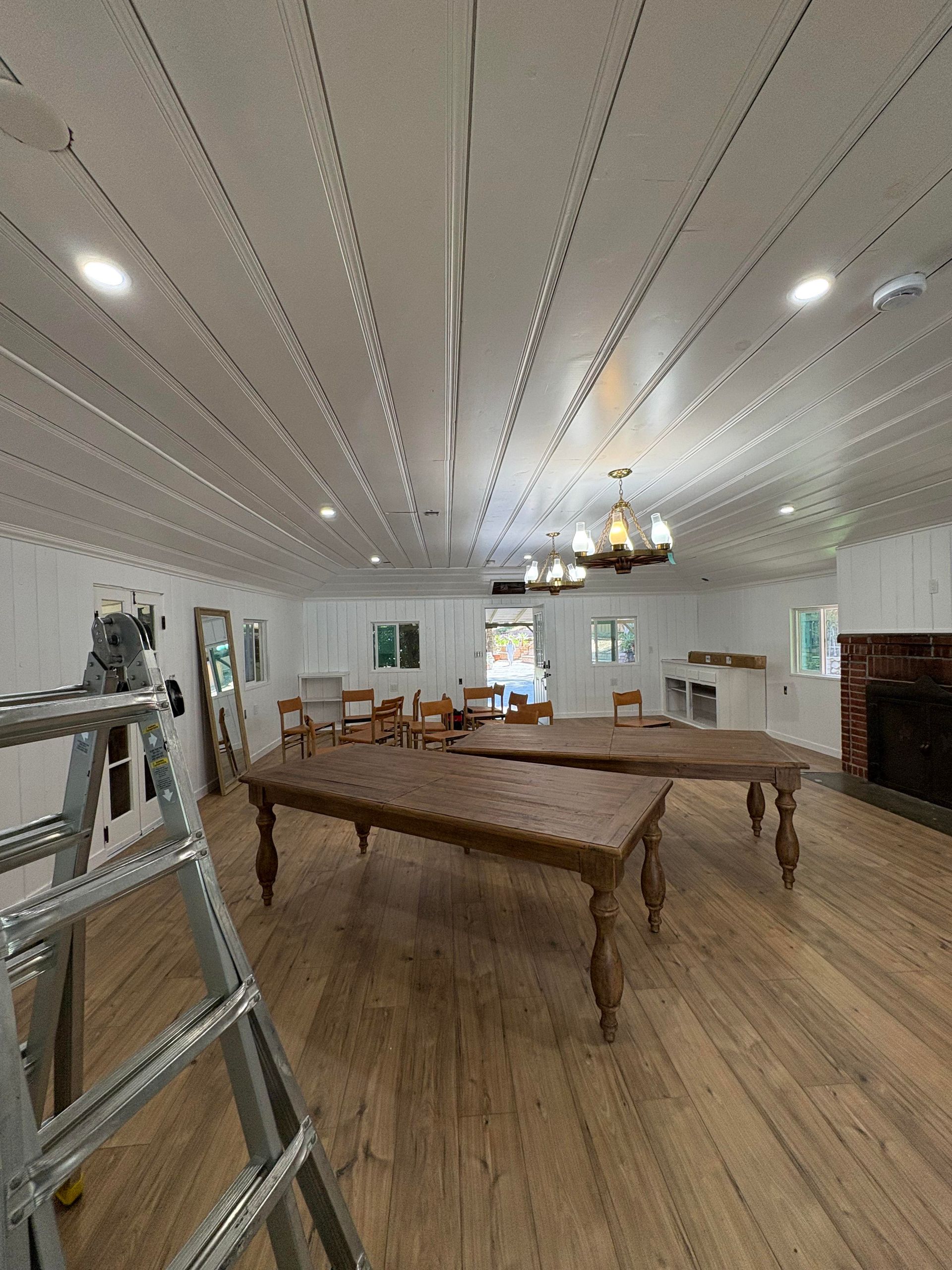 A tall hallway with stairs, ladder, and a light fixture on the ceiling.