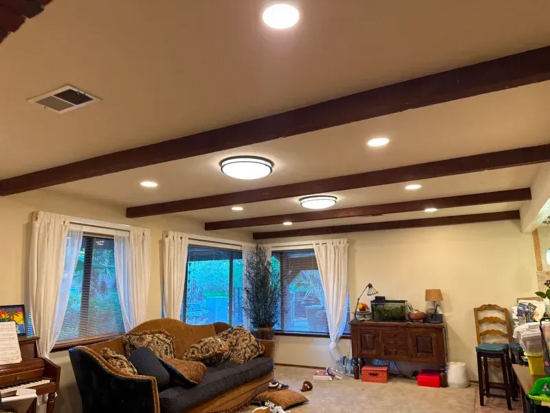 Living room with a sofa, windows, and decorative ceiling beams.