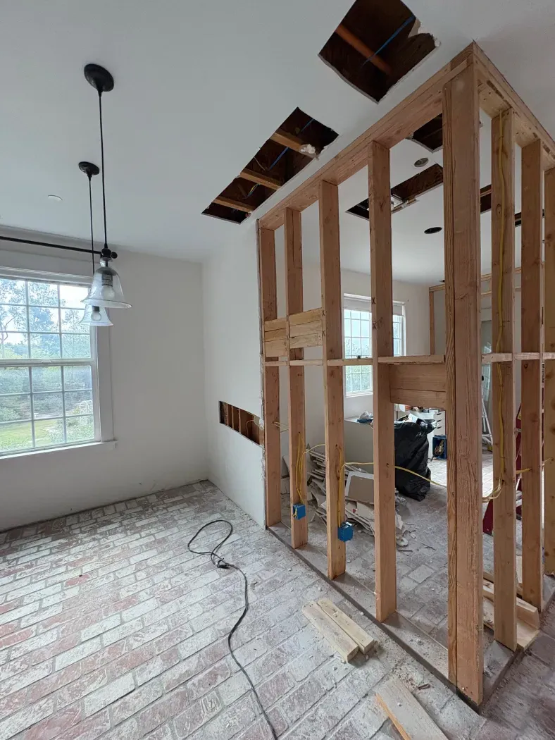 Room under renovation with exposed studs, holes in the ceiling, and wiring.