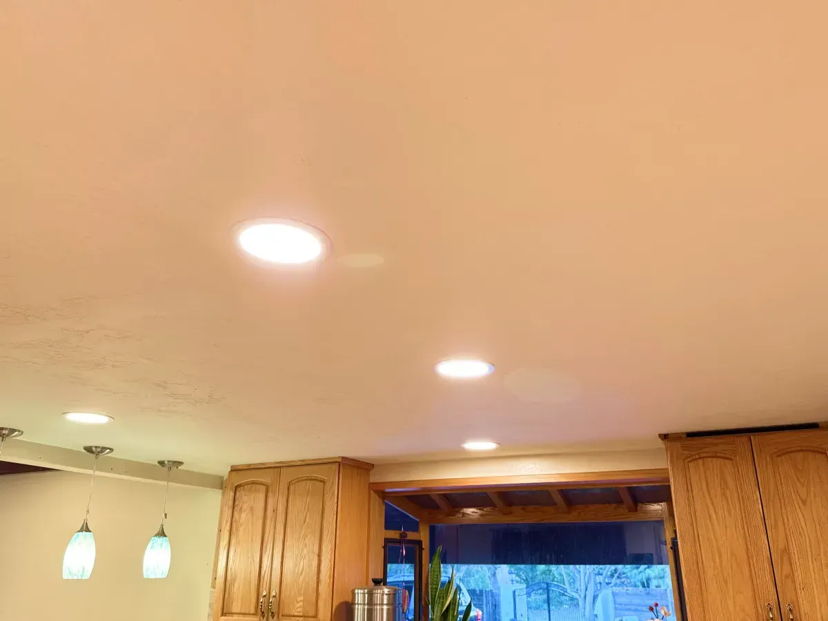 Kitchen ceiling with recessed lights, wooden cabinets, and a window.