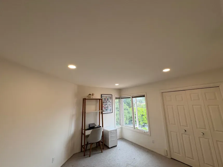 Empty room with desk, window, shelving, and double-door closet. Recessed lighting.