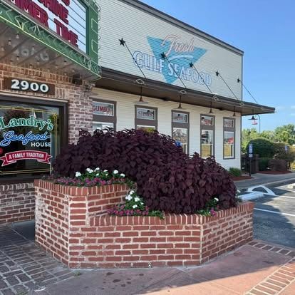 Exterior of Landry's Seafood House restaurant, building with brick facade and flower bed, Fresh Gulf Seafood sign above.