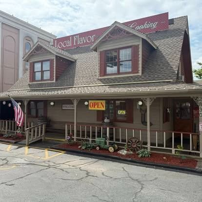 Restaurant with tan siding, red shutters, and a sign that says 