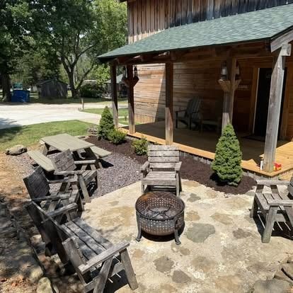 Patio with wooden chairs, fire pit, picnic table, and cabin with porch.