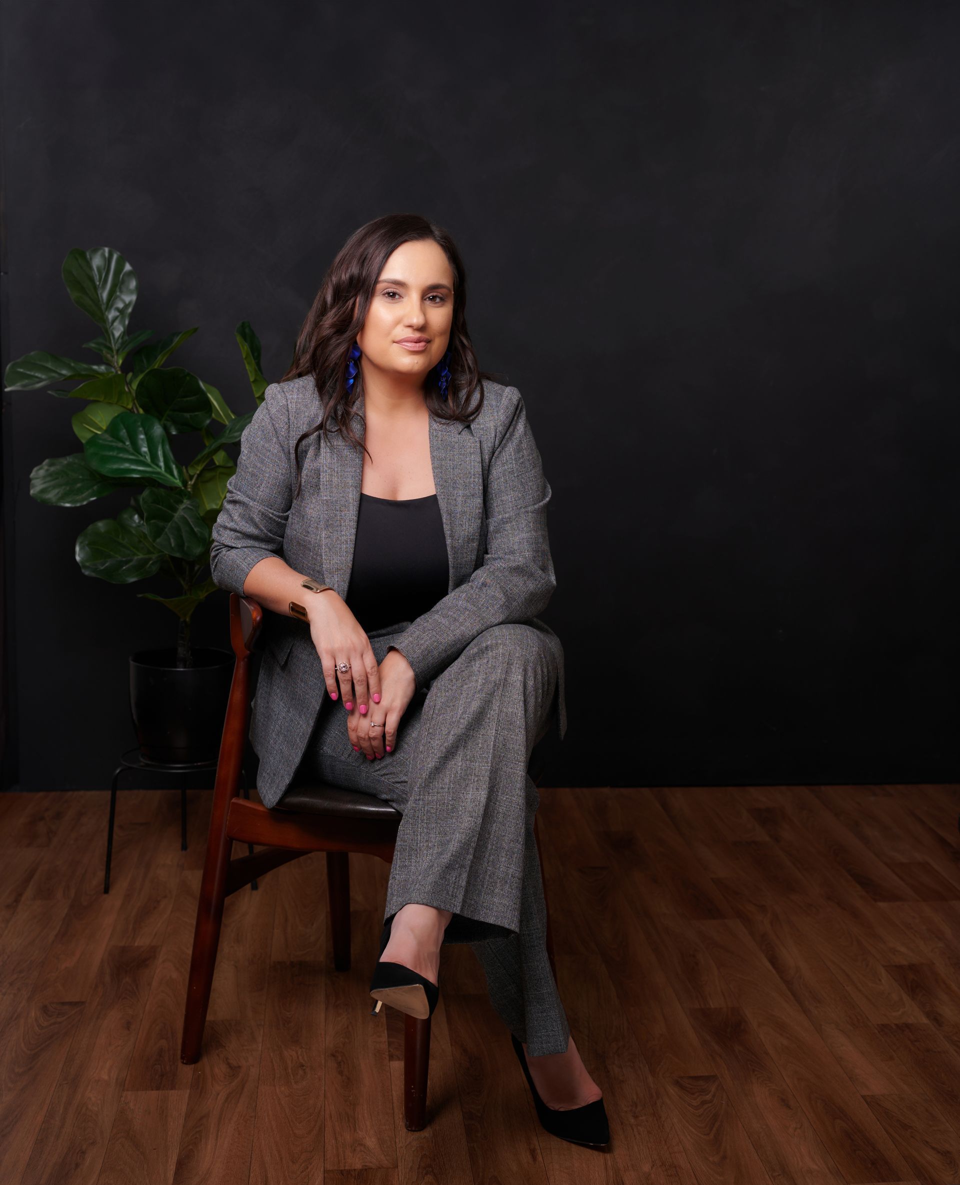 A woman in a suit is sitting in a chair.