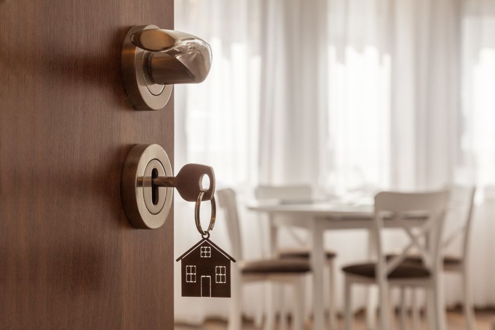 A Door With A Key In It And A Keychain With A House On It — Port Macquarie Locksmiths In Port Macquarie, NSW