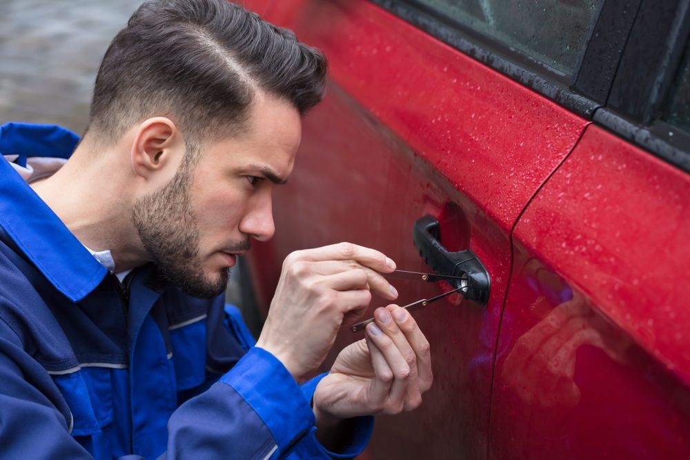 A Man Is Trying To Open A Car Door With A Screwdriver — Port Macquarie Locksmiths In South West Rocks, NSW