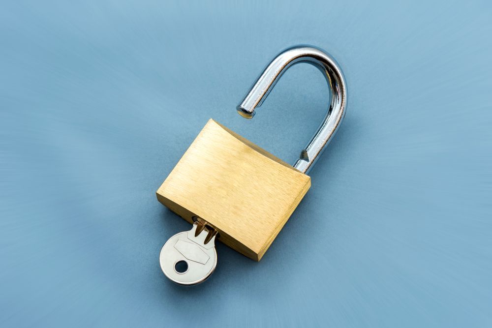 An Open Padlock With A Key Sticking Out Of It On A Blue Background — Port Macquarie Locksmiths In South West Rocks, NSW