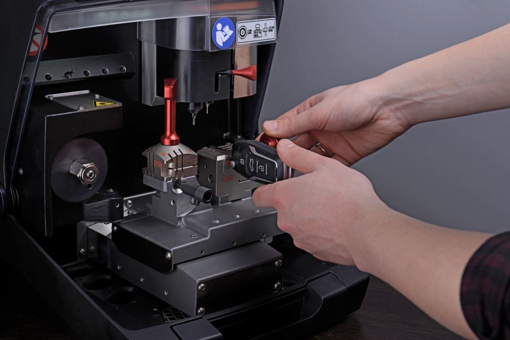 A Person Is Cutting A Key With A Machine — Port Macquarie Locksmiths In Laurieton, NSW