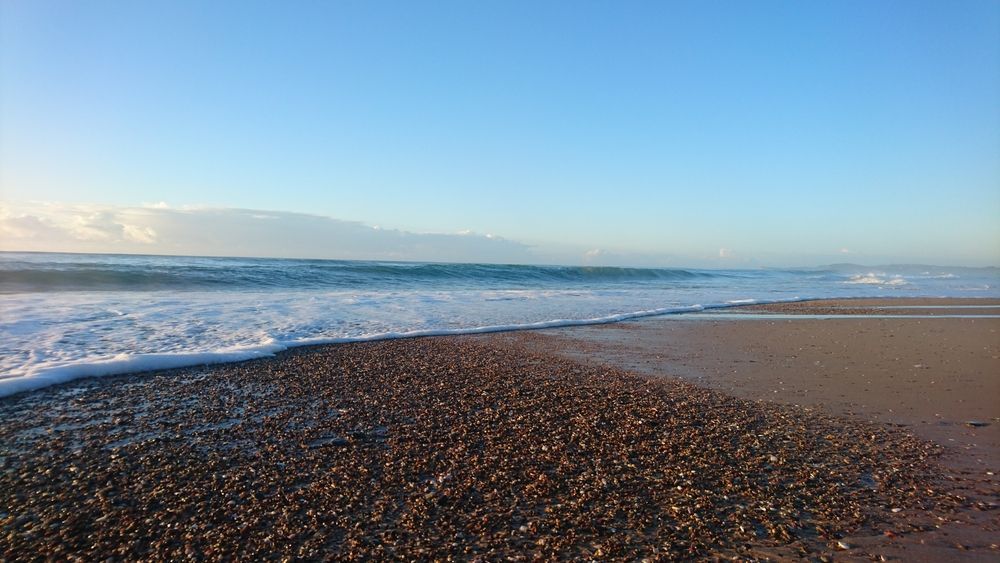A Beach With Waves Crashing On The Shore And A Blue Sky In The Background — Port Macquarie Locksmiths In Lake Cathie, NSW