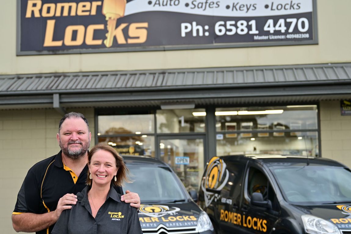 A Man And A Woman Are Standing In Front Of A Store Called Romer Locks — Port Macquarie Locksmiths In Port Macquarie, NSW
