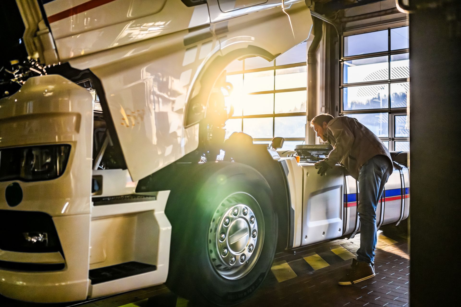 A man is working on a semi truck in a garage.