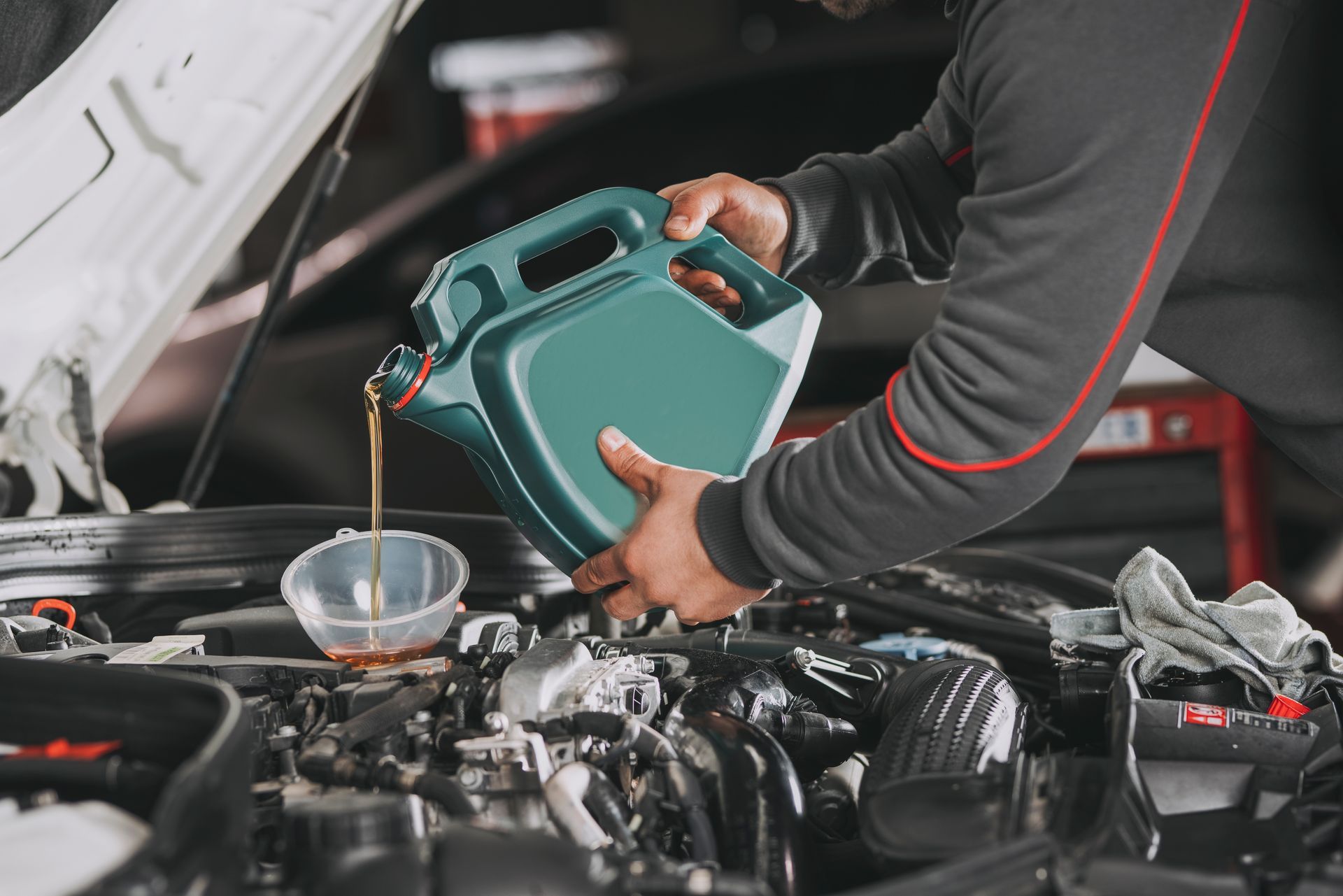 A man is pouring oil into a car engine.