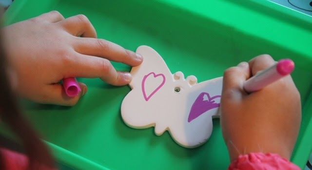 A child is drawing a heart on a cookie with a marker  at Dragonfly crafts parties.