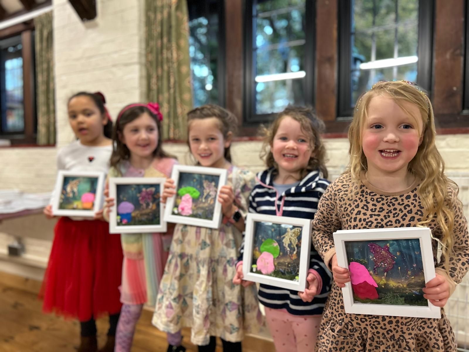 A group of young girls are holding up their paintings at Dragonfly crafts parties
