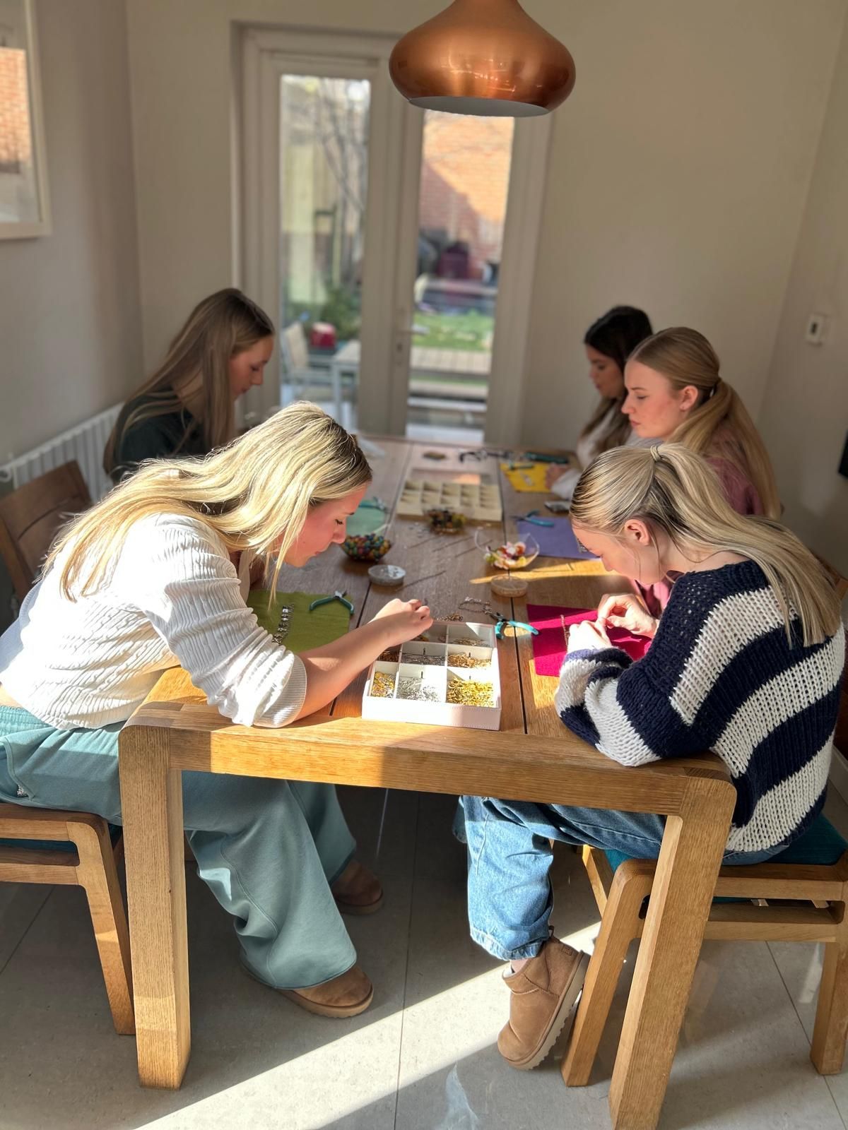 A group of women are sitting at a table in a room for charm party  at Dragonfly crafts parties