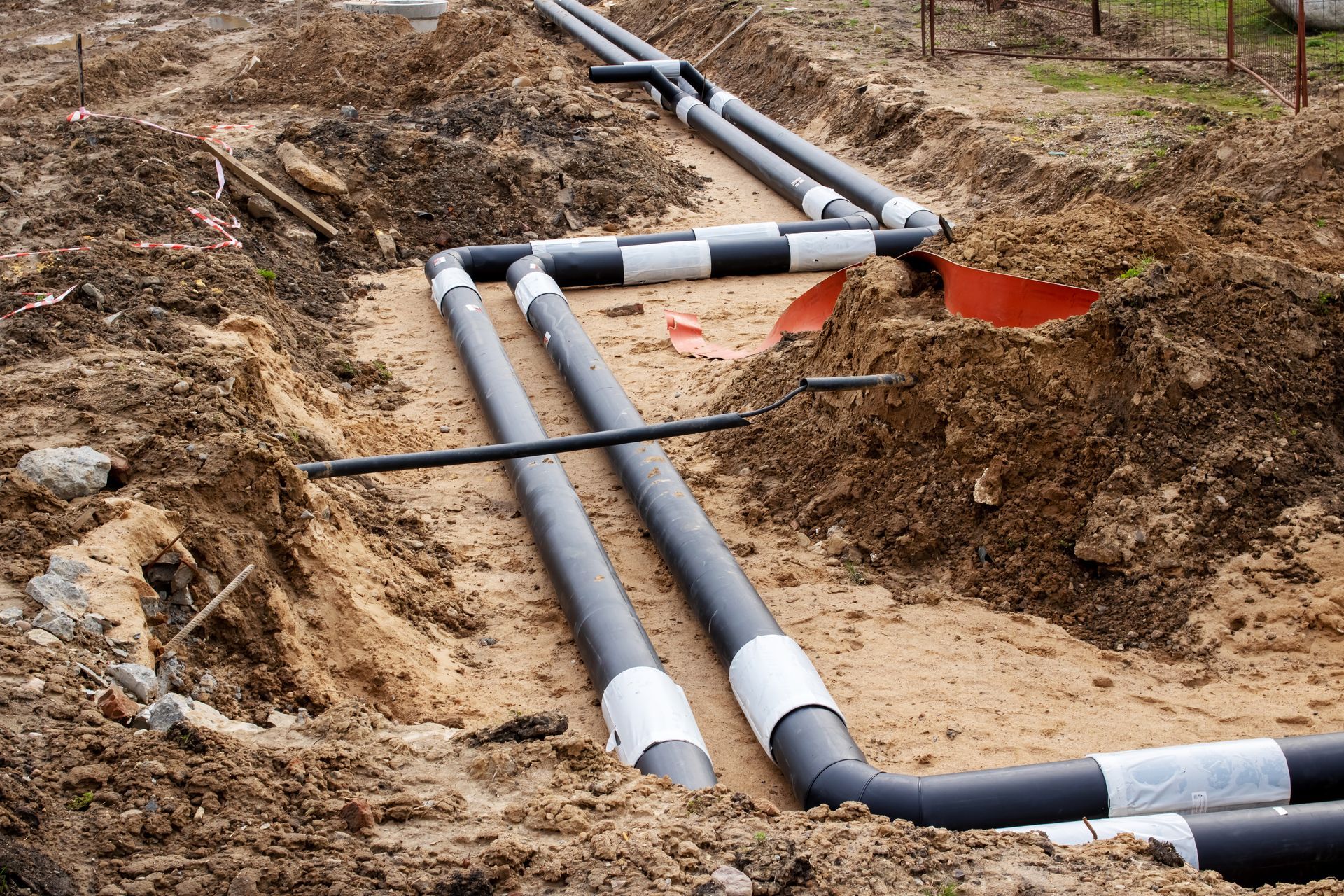 A bunch of pipes are laying in the dirt.