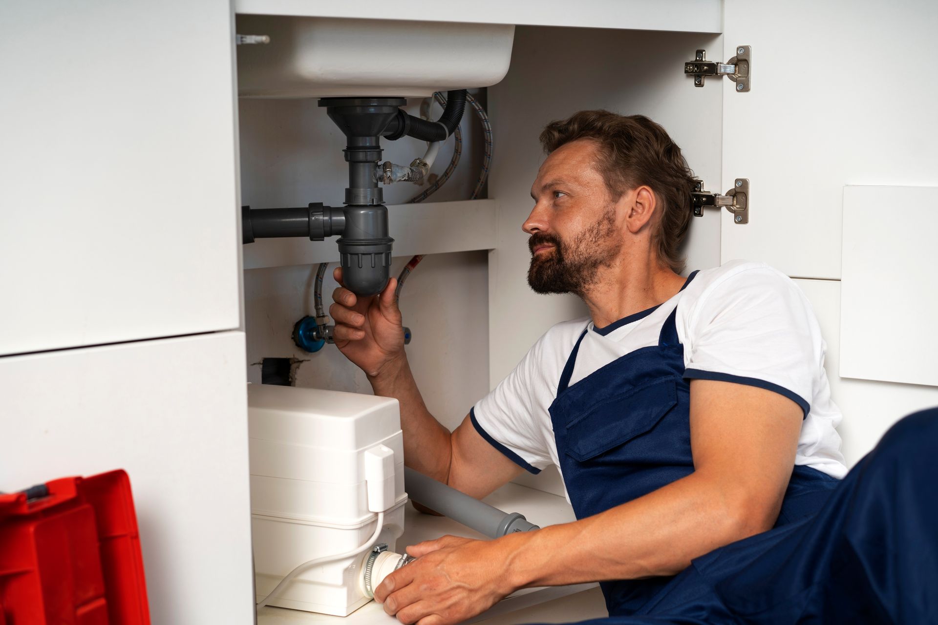 A plumber is fixing a sink in a kitchen.