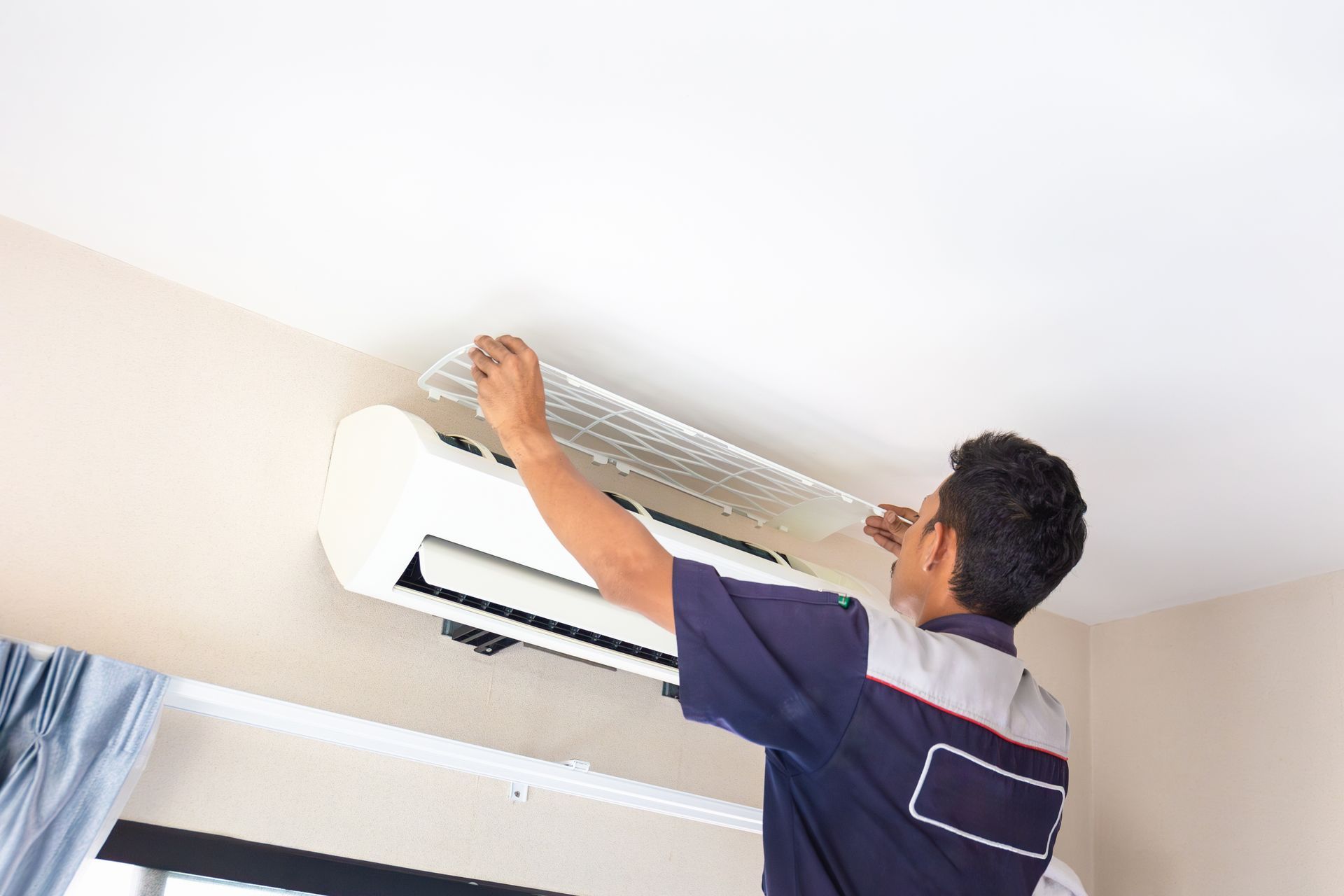 A man is working on an air conditioner in a room.