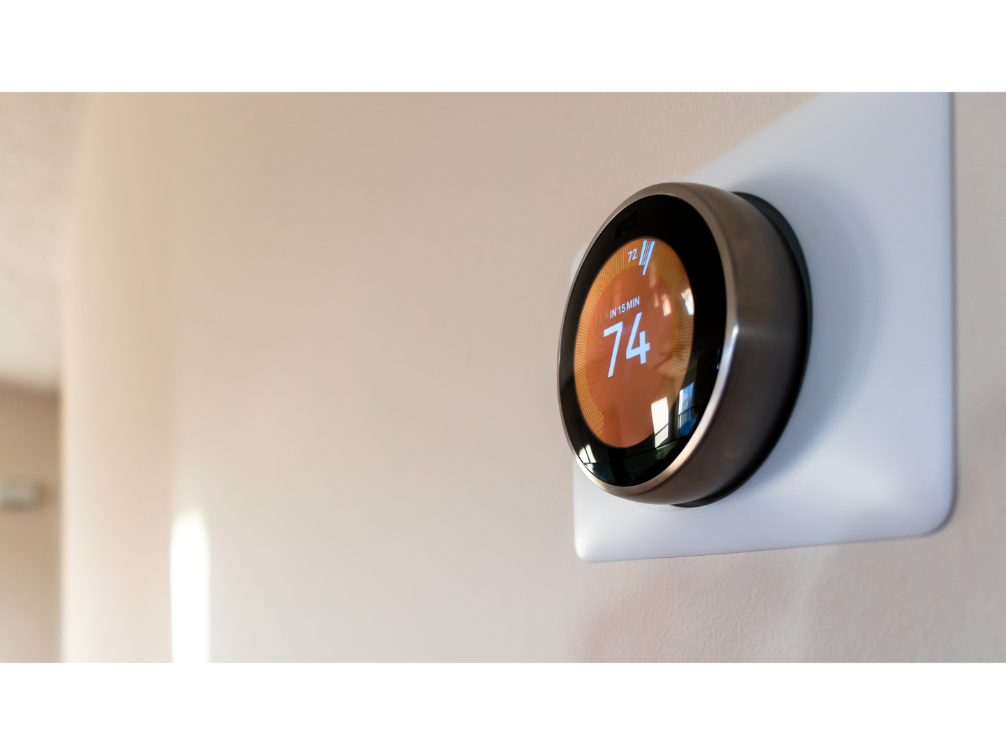A thermostat is mounted on a wall and the temperature is 74 degrees fahrenheit.