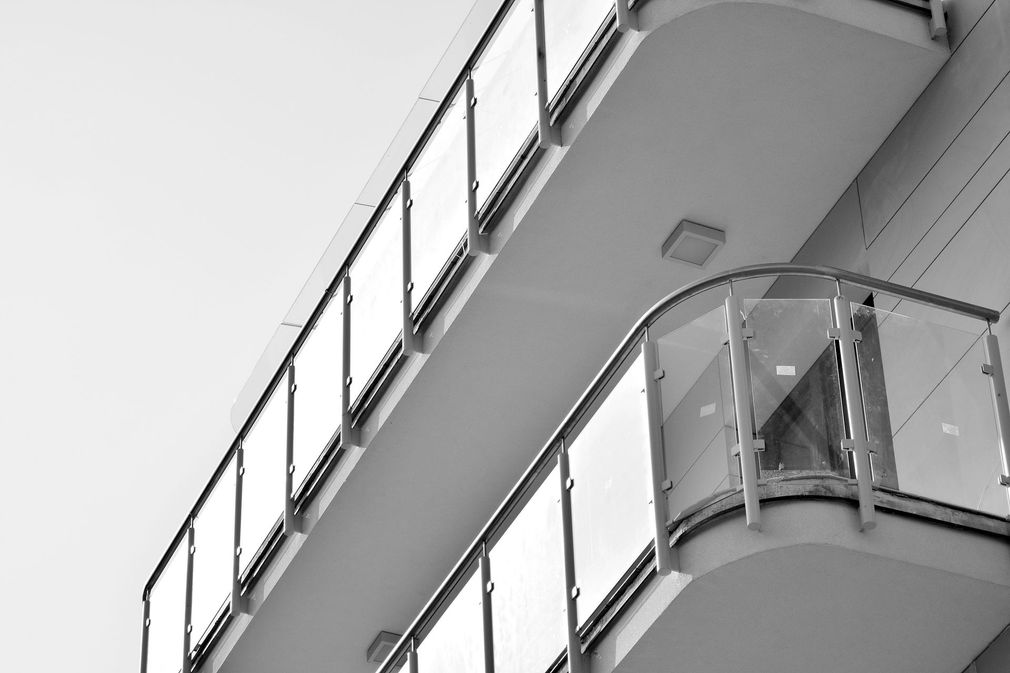 Veduta in bianco e nero di un edificio moderno con balconi curvi e ringhiere in vetro.