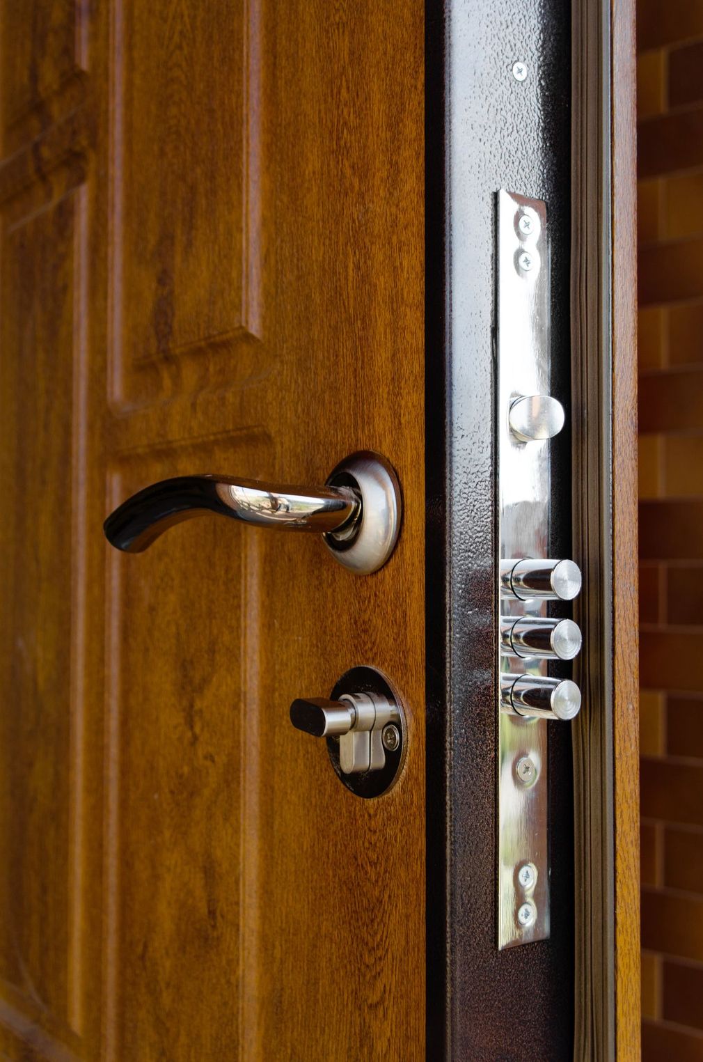 Porta d'ingresso in legno con maniglia nera e serratura argentata leggermente aperta